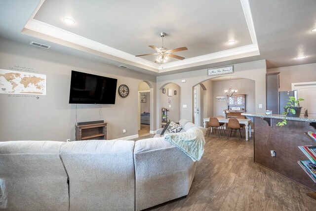 6108 Copper Sky Ct, Midland, TX 79705 - living room with a raised ceiling, arched walkways, a ceiling fan, wood finished floors, and a chandelier