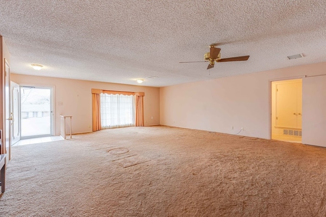 carpeted spare room with ceiling fan, a wealth of natural light, and a textured ceiling