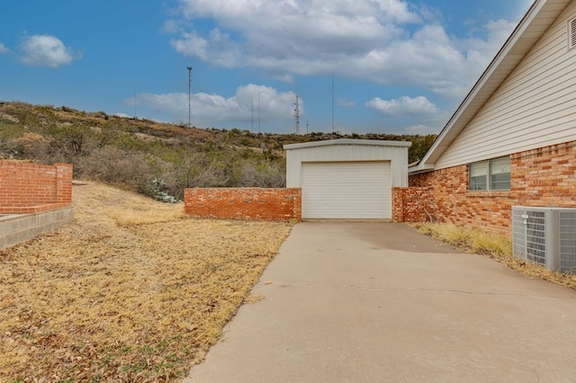 view of yard with central AC unit, a garage, and an outdoor structure