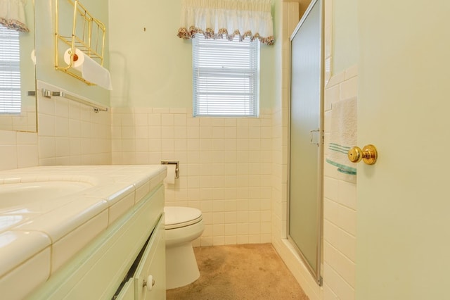 bathroom with vanity, toilet, tile walls, and a shower with shower door