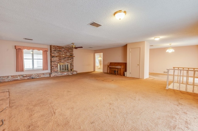 unfurnished living room with ceiling fan, light colored carpet, a textured ceiling, and a fireplace