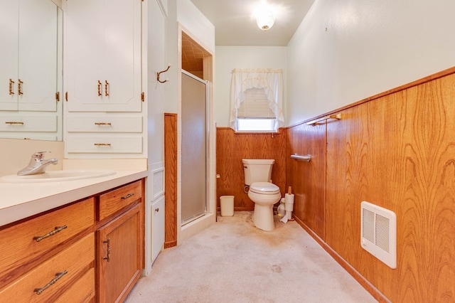 bathroom with toilet, vanity, wooden walls, and a shower with shower door