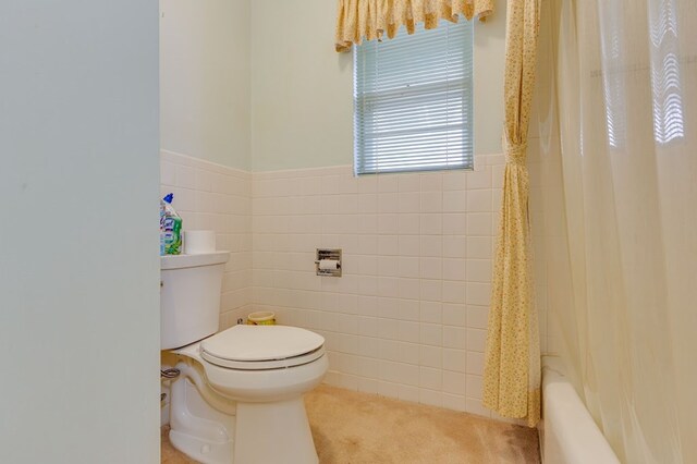 bathroom featuring tile walls, toilet, and shower / tub combo with curtain