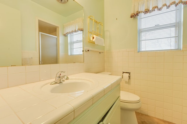 bathroom with tile walls, vanity, toilet, and walk in shower