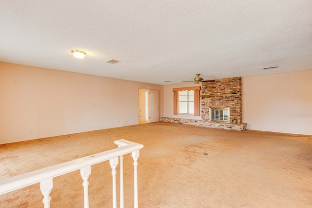 unfurnished living room featuring ceiling fan, a fireplace, carpet floors, and a textured ceiling