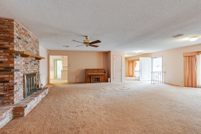 unfurnished living room with ceiling fan, a brick fireplace, light colored carpet, and a textured ceiling