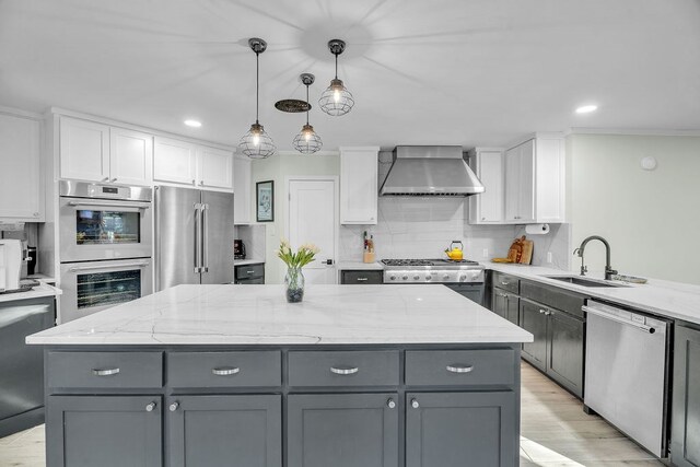 kitchen with appliances with stainless steel finishes, wall chimney exhaust hood, gray cabinets, and white cabinets