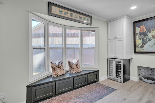 living area with plenty of natural light, beverage cooler, light wood-style floors, and baseboards