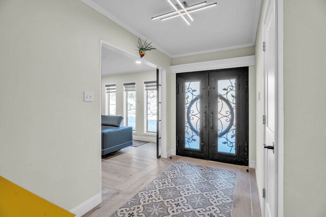 entrance foyer featuring french doors, baseboards, light wood-style floors, and ornamental molding