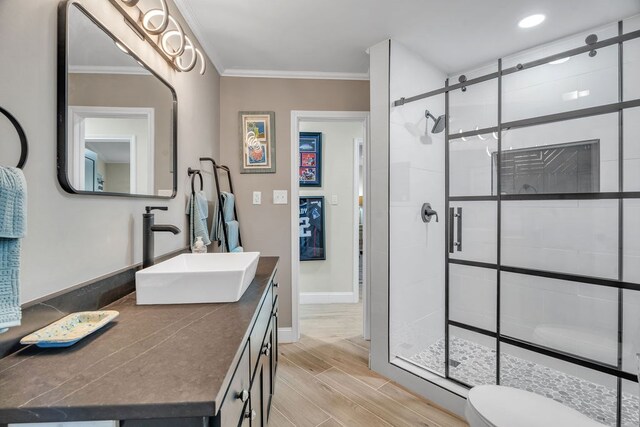 full bathroom featuring vanity, baseboards, wood tiled floor, a stall shower, and ornamental molding