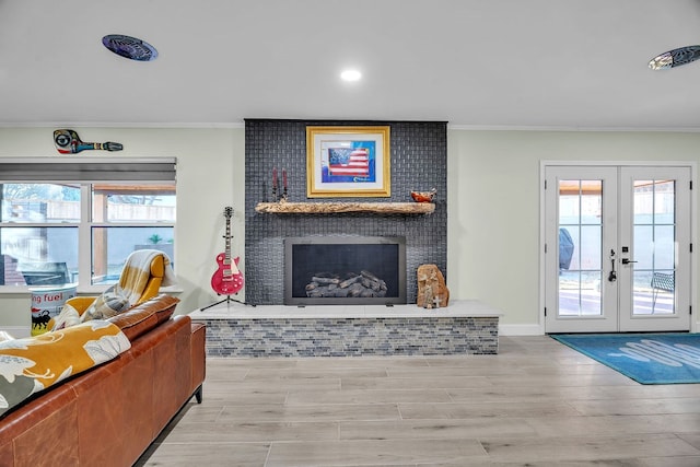 living area featuring a healthy amount of sunlight, french doors, ornamental molding, and a brick fireplace