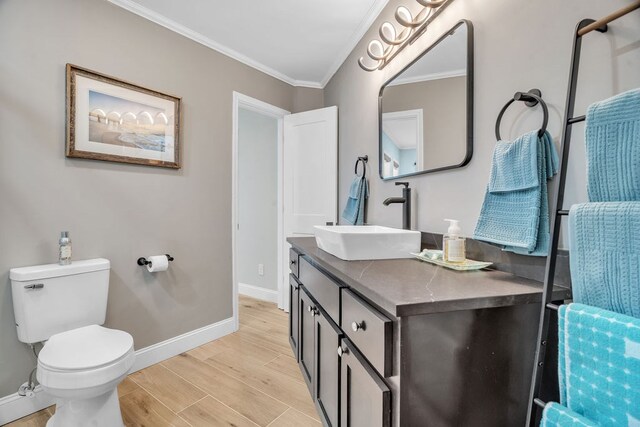 full bath featuring vanity, wood finished floors, baseboards, crown molding, and toilet