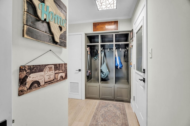 mudroom with visible vents, ornamental molding, and light wood finished floors