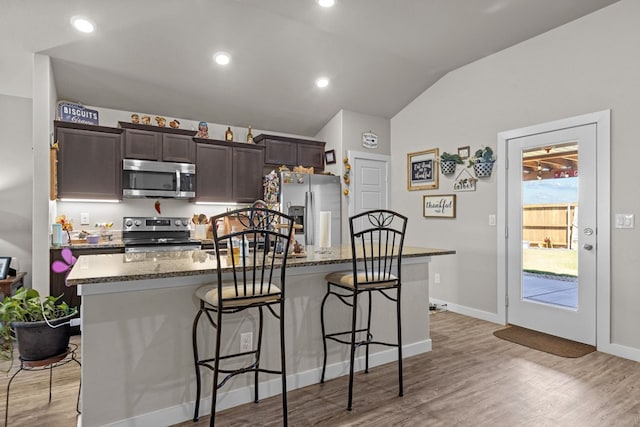 1201 Bajada St, Midland, TX 79705 - kitchen featuring stainless steel appliances, a center island with sink, dark brown cabinets, a breakfast bar area, and lofted ceiling