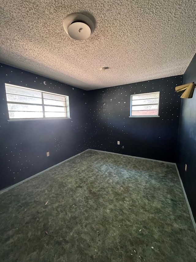 carpeted empty room featuring plenty of natural light and a textured ceiling