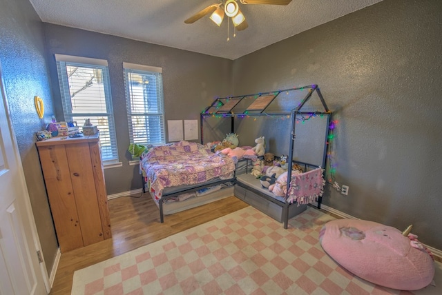 bedroom with hardwood / wood-style floors, a textured ceiling, and ceiling fan