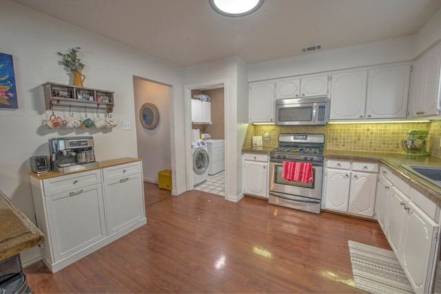 kitchen with stainless steel appliances, white cabinets, and independent washer and dryer