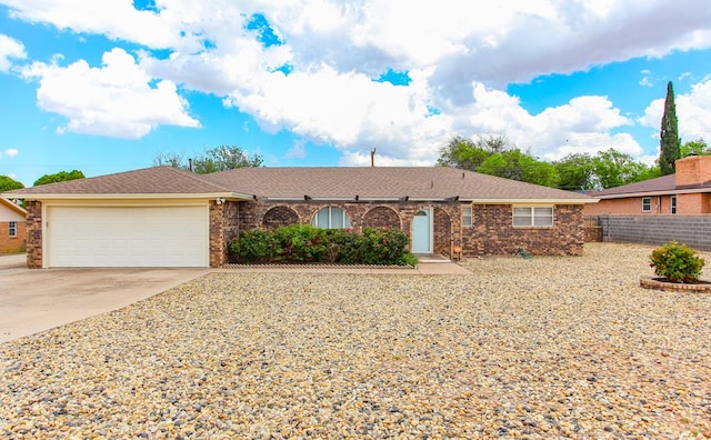 ranch-style home with concrete driveway, brick siding, an attached garage, and fence