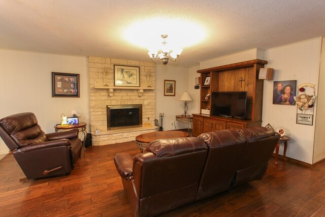 living room featuring a textured ceiling, baseboards, dark wood-style flooring, a stone fireplace, and an inviting chandelier