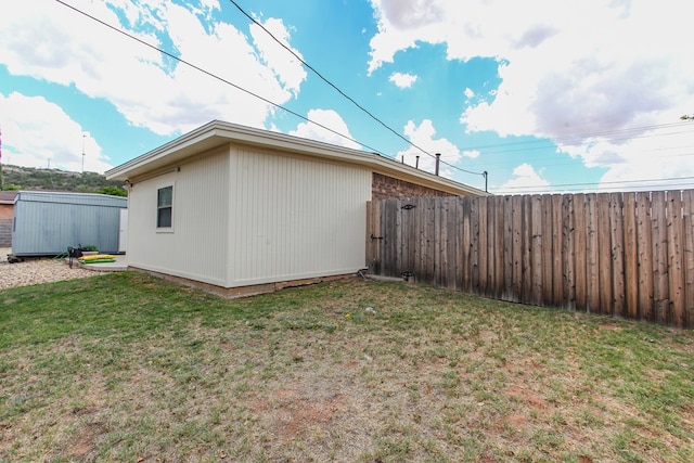 view of property exterior featuring a fenced backyard, an outbuilding, and a lawn
