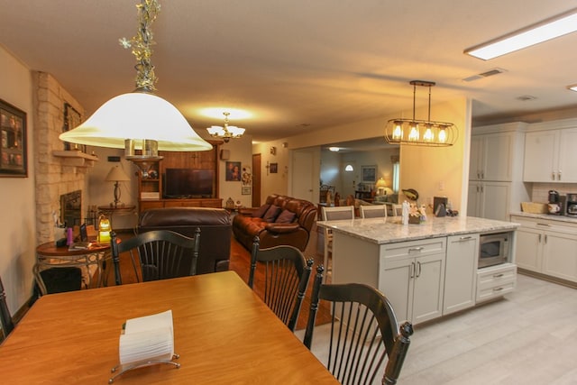 dining area with light wood-type flooring, an inviting chandelier, and visible vents