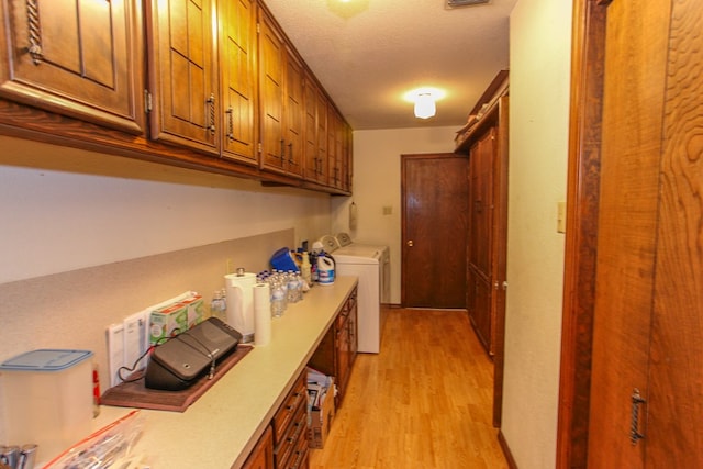 corridor featuring light wood finished floors, visible vents, and washer and dryer