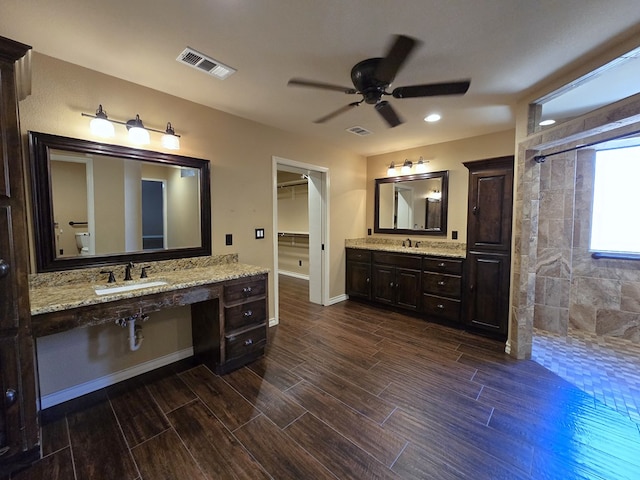 bathroom with ceiling fan, a tile shower, and vanity