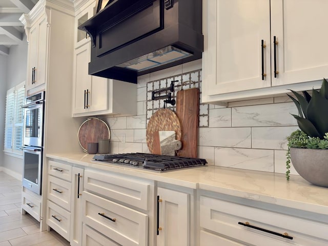 5516 E County Rd 93, Midland, TX 79706 - kitchen featuring appliances with stainless steel finishes, extractor fan, white cabinets, tasteful backsplash, and light stone counters