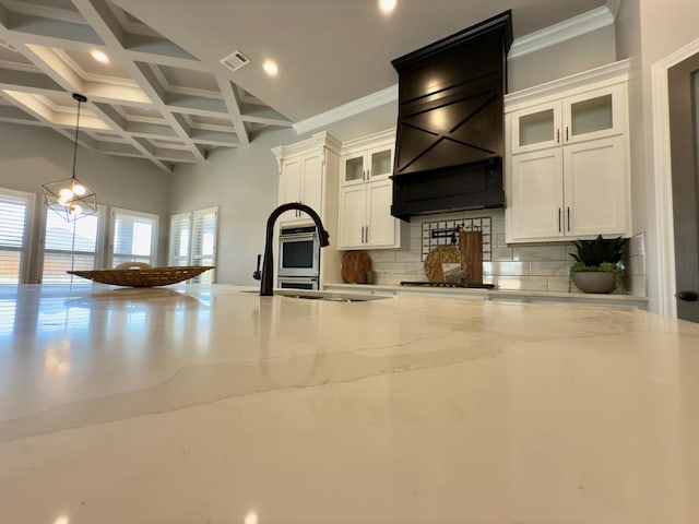 5516 E County Rd 93, Midland, TX 79706 - kitchen with tasteful backsplash, beam ceiling, white cabinetry, light stone countertops, and custom range hood