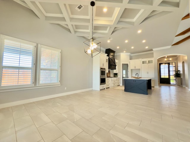 5516 E County Rd 93, Midland, TX 79706 - kitchen with arched walkways, open floor plan, a center island with sink, beamed ceiling, and crown molding