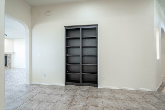 4906 Meadowside St, Midland, TX 79705 - unfurnished room with arched walkways, light tile patterned floors, and a stone fireplace