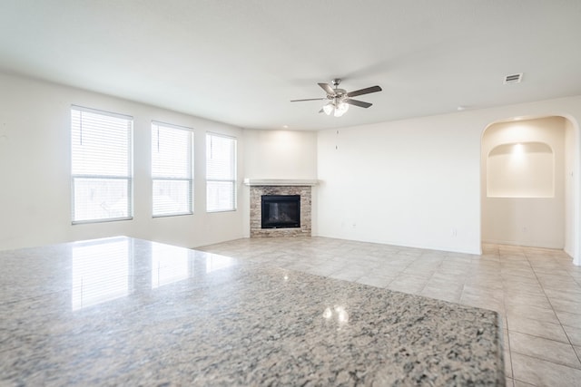 4906 Meadowside St, Midland, TX 79705 - unfurnished living room featuring a ceiling fan, a fireplace, arched walkways, and light tile patterned floors