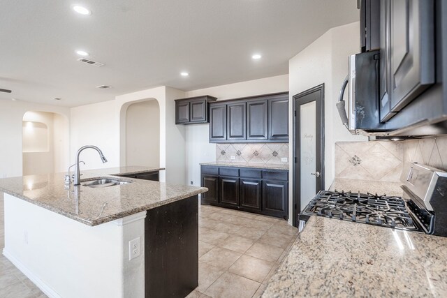 4906 Meadowside St, Midland, TX 79705 - kitchen with arched walkways, stainless steel appliances, an island with sink, light stone counters, and backsplash