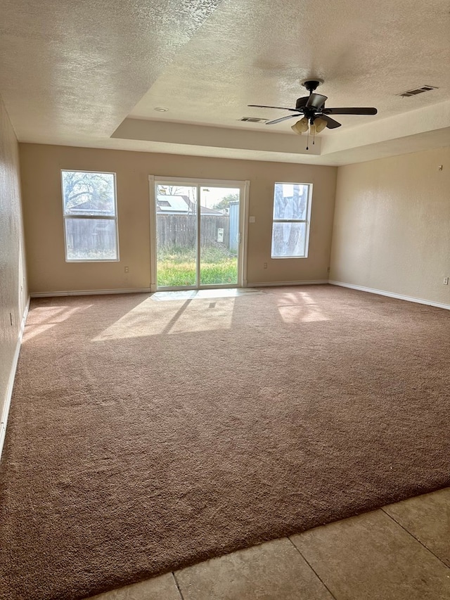 carpeted spare room with a textured ceiling, a raised ceiling, plenty of natural light, and ceiling fan