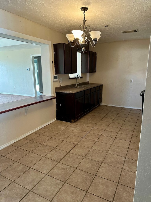 kitchen with dark brown cabinets, a textured ceiling, sink, a chandelier, and hanging light fixtures