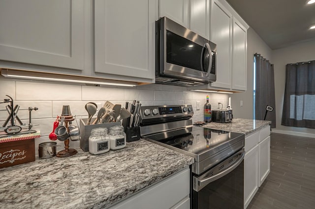 6909 Moonlight, Midland, TX 79705 - kitchen with decorative backsplash, white cabinets, light stone countertops, baseboards, and appliances with stainless steel finishes