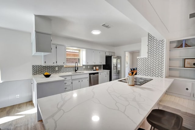 2 Auburn Ct, Midland, TX 79705 - kitchen with a sink, a peninsula, wood finished floors, light stone counters, and appliances with stainless steel finishes