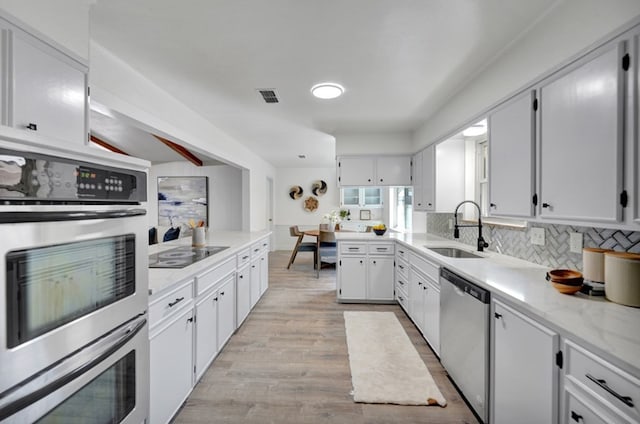 2 Auburn Ct, Midland, TX 79705 - kitchen with visible vents, a sink, decorative backsplash, stainless steel appliances, and light wood-type flooring