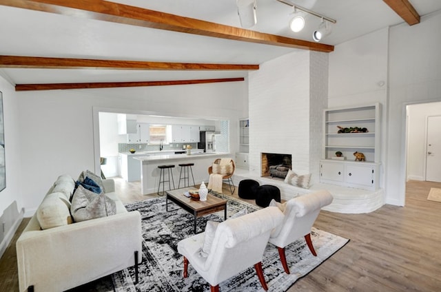 2 Auburn Ct, Midland, TX 79705 - living area featuring baseboards, a brick fireplace, light wood-style flooring, and vaulted ceiling with beams