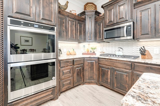 4506 San Pedro Ct, Midland, TX 79707 - kitchen with crown molding, dark brown cabinets, light stone countertops, appliances with stainless steel finishes, and backsplash