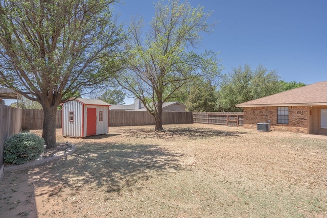 view of yard featuring a fenced backyard, a shed, central AC unit, and an outdoor structure