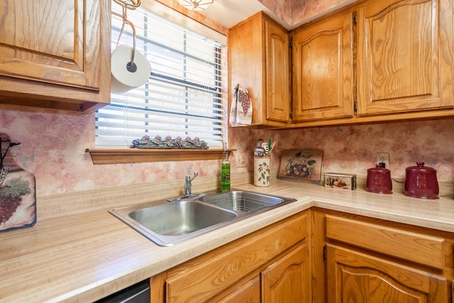 kitchen with light countertops, brown cabinetry, and a sink
