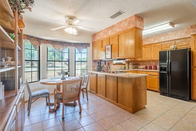 kitchen featuring black refrigerator with ice dispenser, a ceiling fan, visible vents, a peninsula, and light countertops