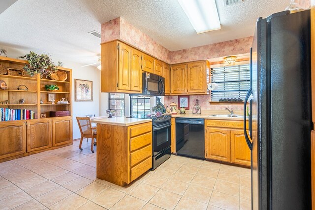 kitchen with a sink, black appliances, a peninsula, light countertops, and a textured ceiling