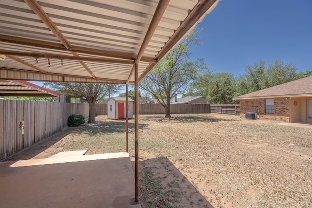 view of yard with a fenced backyard, a shed, an outbuilding, and a patio area