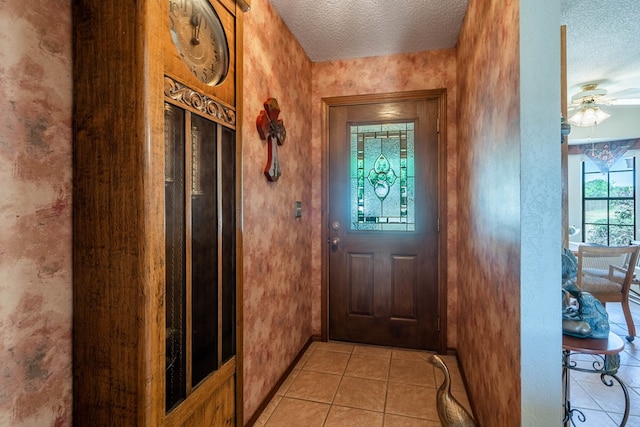 entryway with a textured ceiling, ceiling fan, and light tile patterned flooring