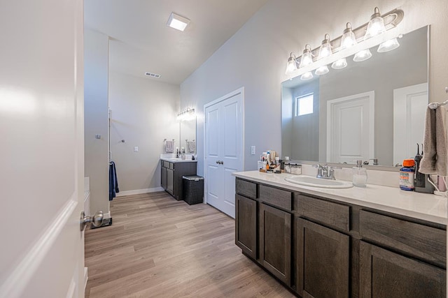 6803 Leather Ln, Midland, TX 79705 - bathroom featuring wood finished floors, two vanities, and baseboards