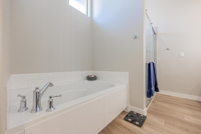 6803 Leather Ln, Midland, TX 79705 - full bath featuring wood finished floors, a bath, a stall shower, and baseboards