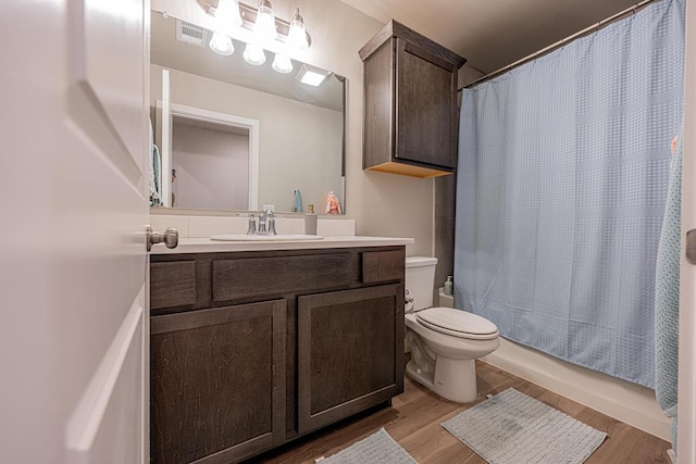 6803 Leather Ln, Midland, TX 79705 - bathroom with toilet, wood finished floors, vanity, and shower / tub combo with curtain