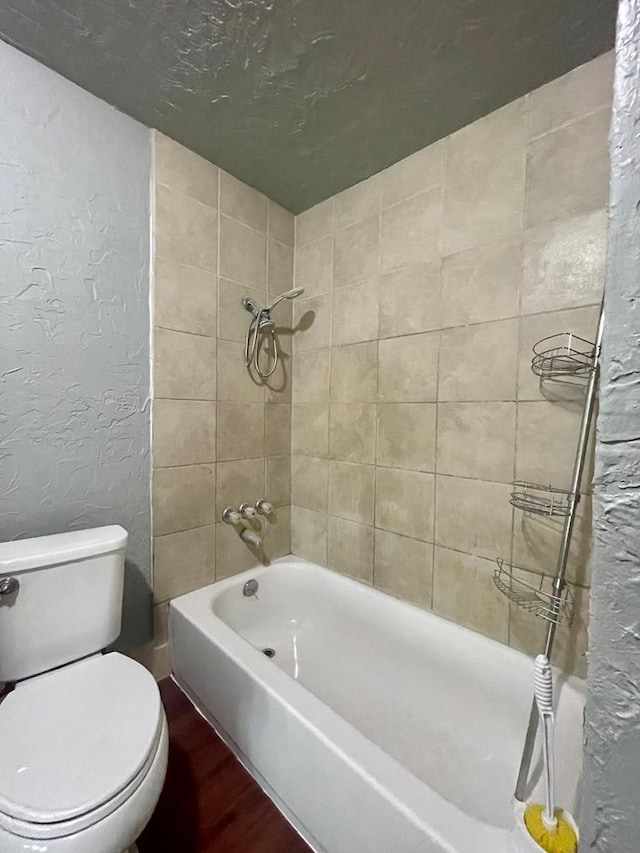 bathroom featuring toilet and tiled shower / bath